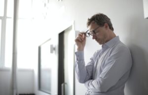 Man holding glasses off his face while stressed