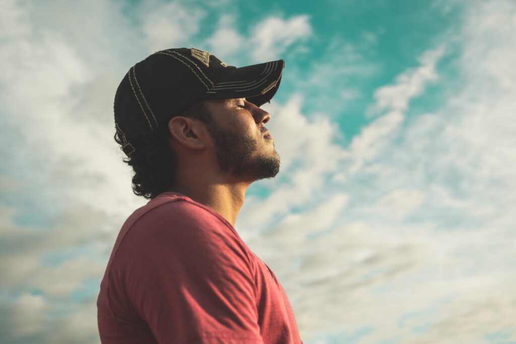 A man breathing in the outdoors, with his eyes closed