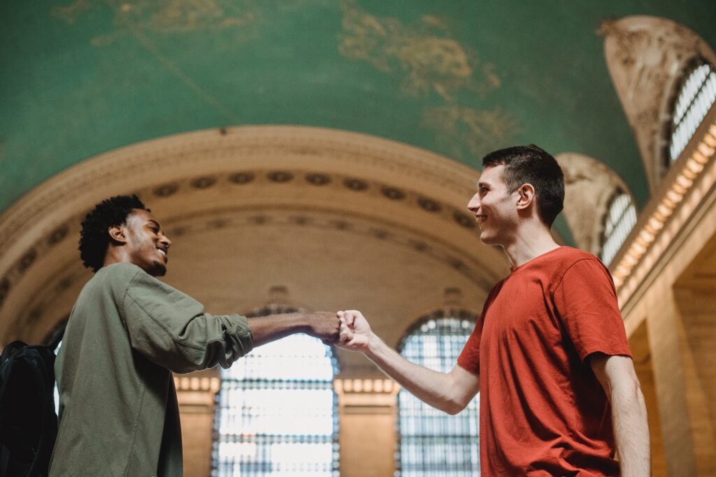 Two employees of different ethnicity fist-bumping one another 